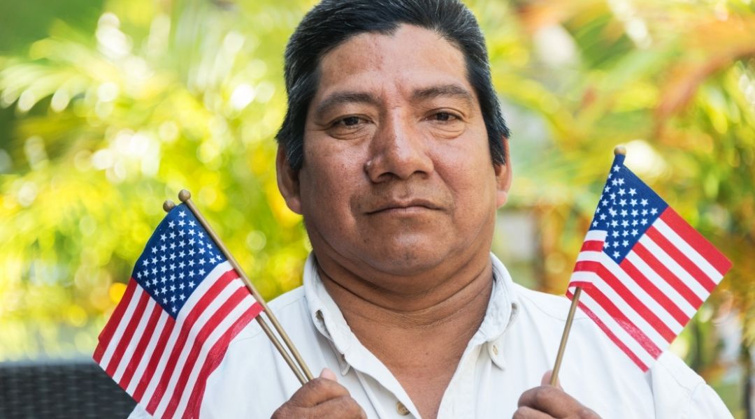 imigrante segurando duas bandeirinhas dos estados unidos